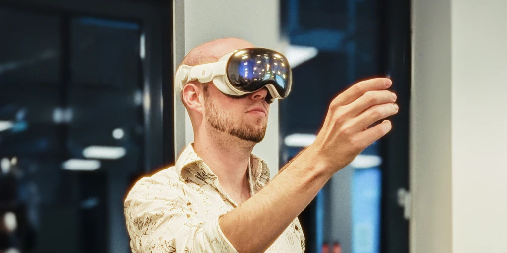 A young man with XR glasses makes a gesture.