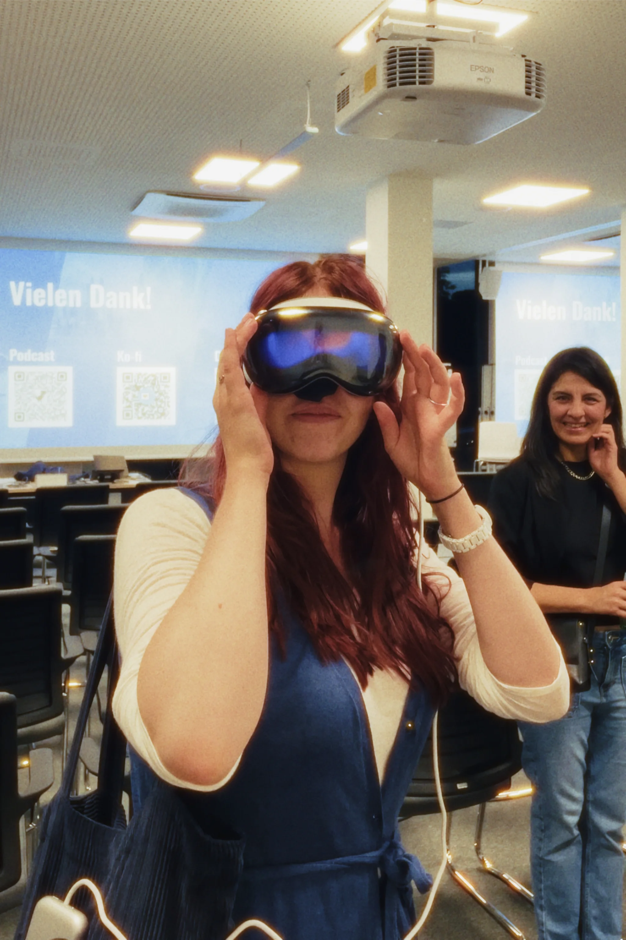 A woman with red hair looks through an Apple Vision Pro.