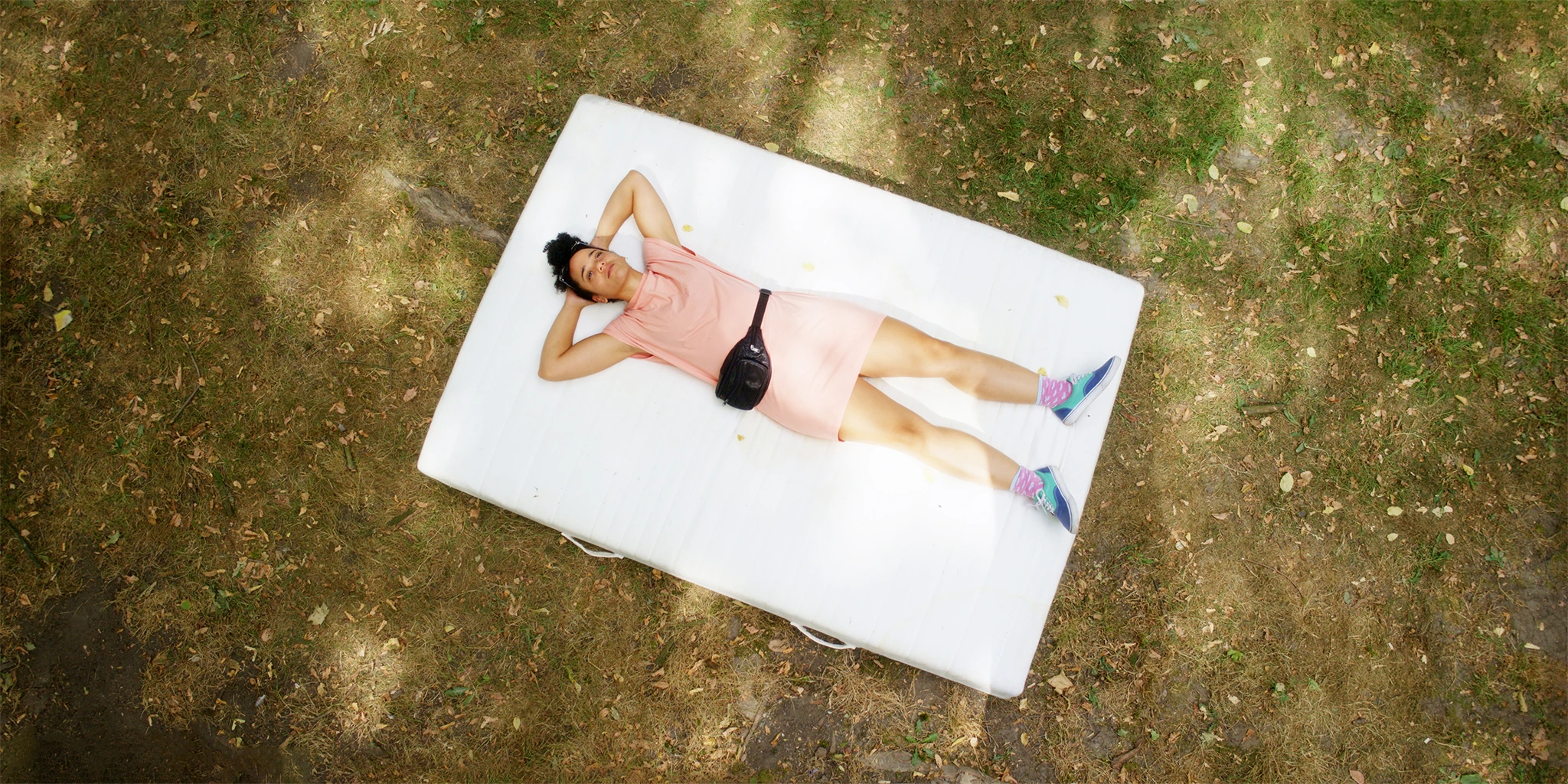 Lena (Shari Asha Crosson) lies on a mattress in a park. She got it for free and wants to use it to furnish the room for her child.