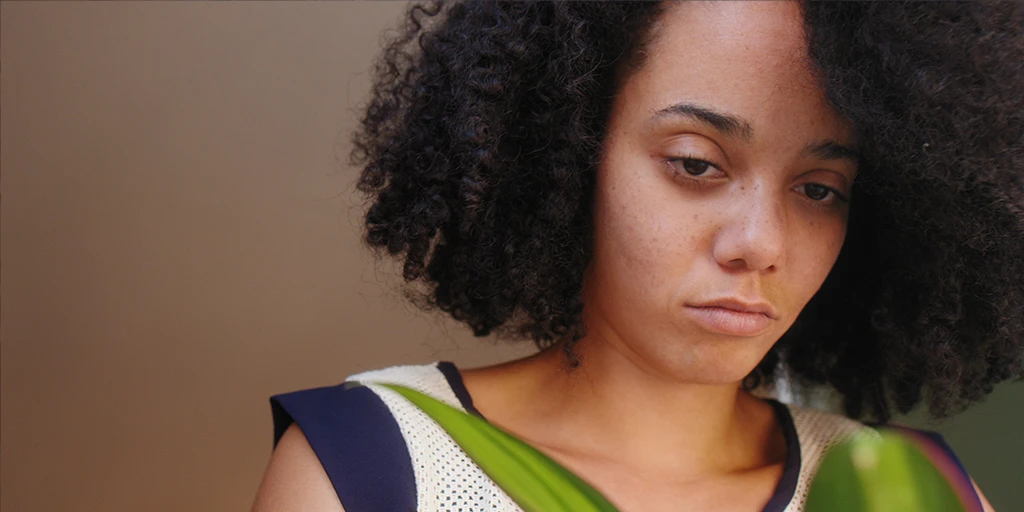 The protagonist of the film »The Mathematics of Things« looks at a potted plant. She looks melancholically at the plant.