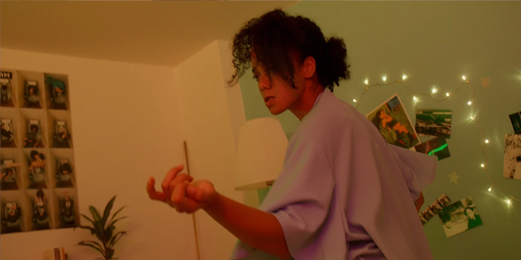 The protagonist of the film »The Mathematics of Things«, Lena (Shari Asha Crosson) dances exuberantly in the newly furnished nursery. She has already painted the wall. Various pictures and posters hang on the wall behind her.